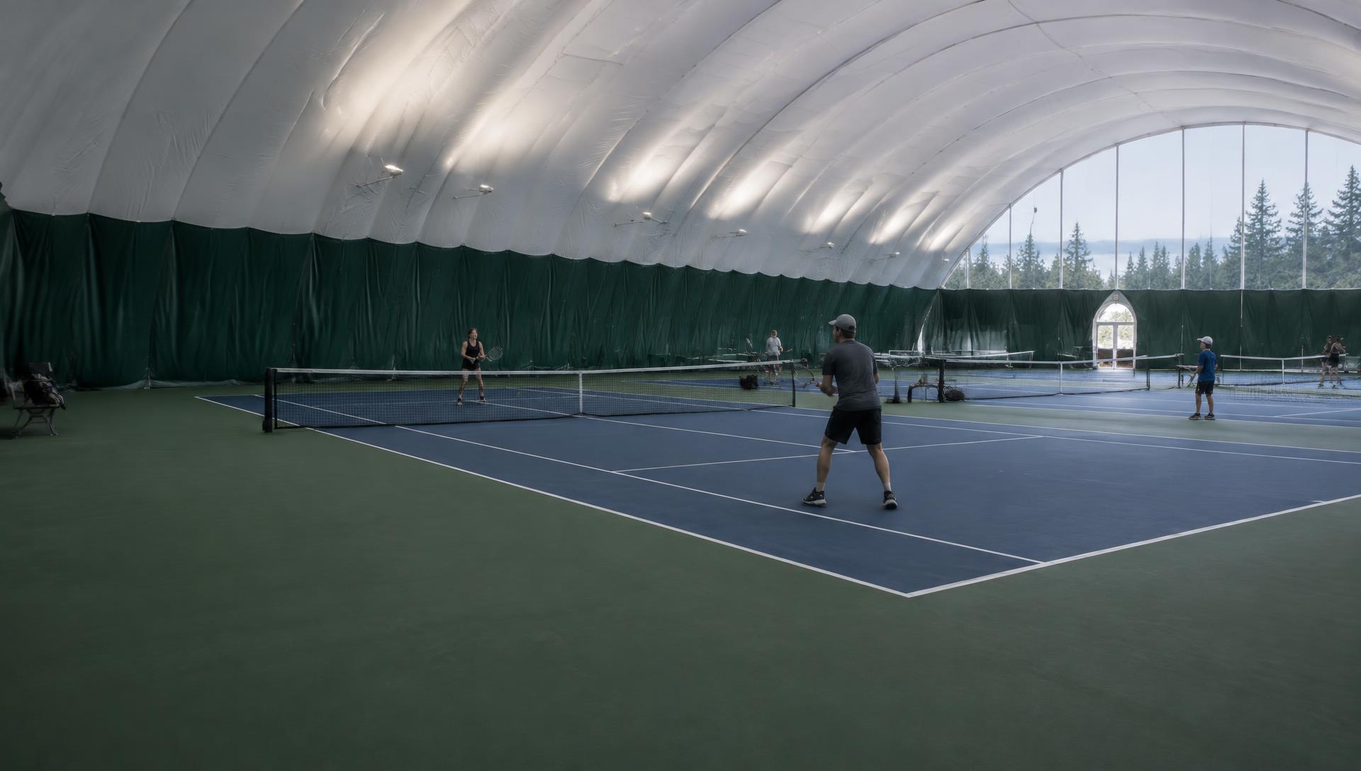 Community players on indoor tennis courts beneath an air-supported roof